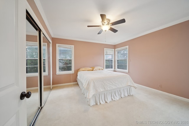 bedroom featuring ornamental molding, a closet, light colored carpet, and baseboards