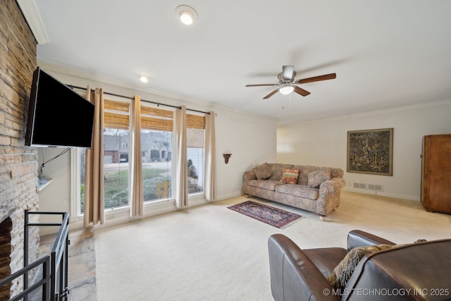 living room with carpet floors, a fireplace, visible vents, ornamental molding, and ceiling fan