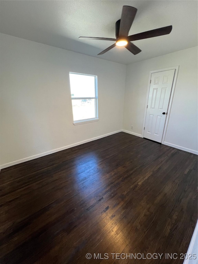 spare room with dark wood-style floors, baseboards, and a ceiling fan