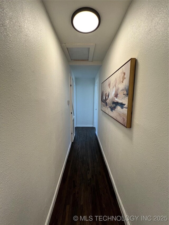 hallway with attic access, baseboards, and dark wood finished floors