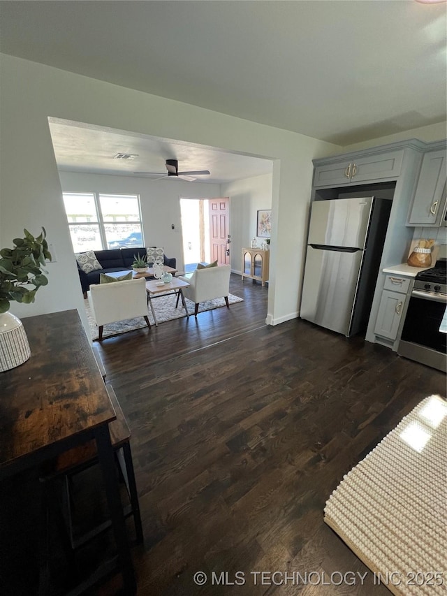 kitchen with dark wood finished floors, stainless steel appliances, gray cabinets, light countertops, and open floor plan