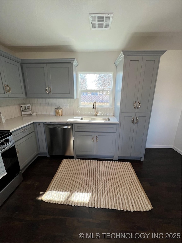 kitchen featuring stainless steel appliances, a sink, visible vents, gray cabinets, and tasteful backsplash