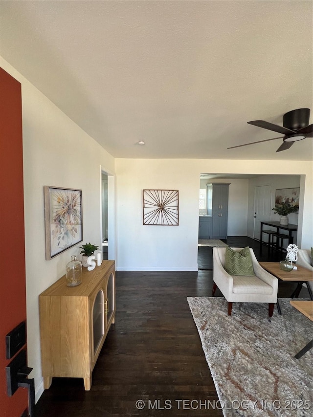 interior space featuring ceiling fan, dark wood-style flooring, and baseboards