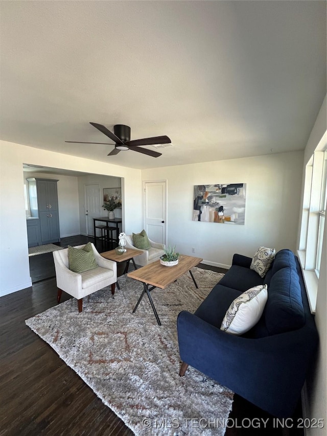 living area featuring dark wood-type flooring, a ceiling fan, and baseboards