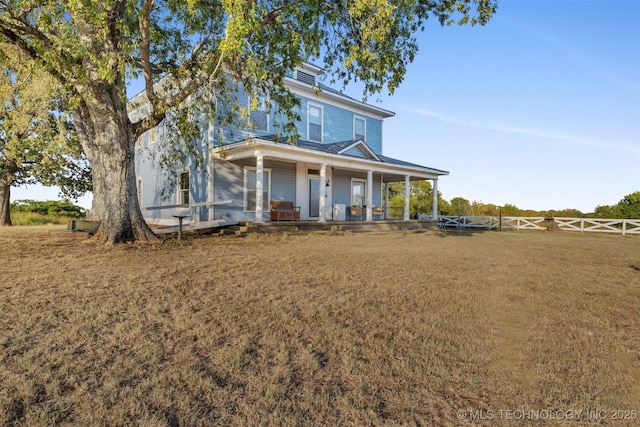 view of front of house with a front yard, covered porch, and fence