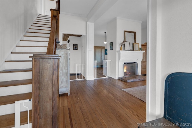 foyer entrance featuring stairway, wood-type flooring, crown molding, and a lit fireplace