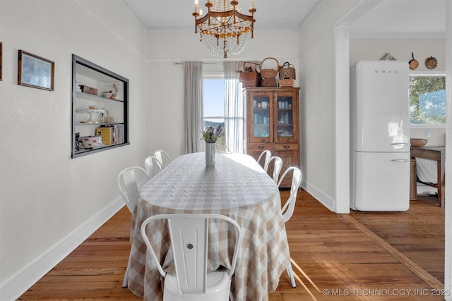 dining room featuring baseboards, ornamental molding, a chandelier, and wood finished floors