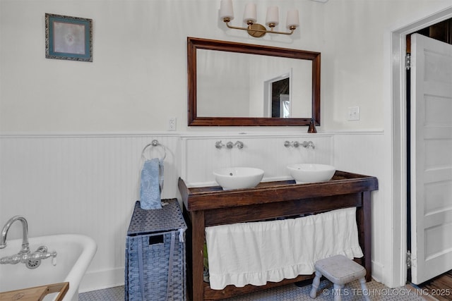 full bathroom featuring wainscoting, a sink, a freestanding bath, and double vanity