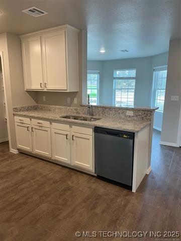 kitchen with dark wood finished floors, black dishwasher, a peninsula, white cabinets, and a sink