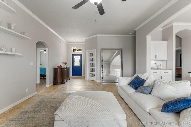 living area featuring ornamental molding, arched walkways, ceiling fan, and baseboards