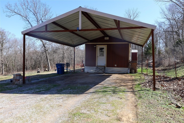 view of outdoor structure with a carport, driveway, and entry steps