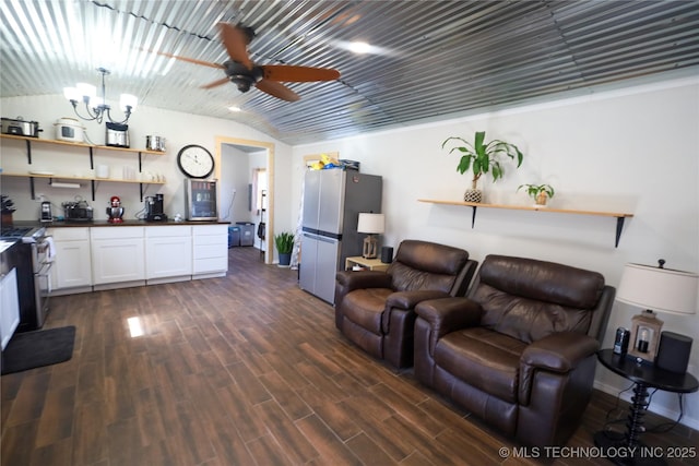 living area with vaulted ceiling, ceiling fan with notable chandelier, and dark wood-style flooring