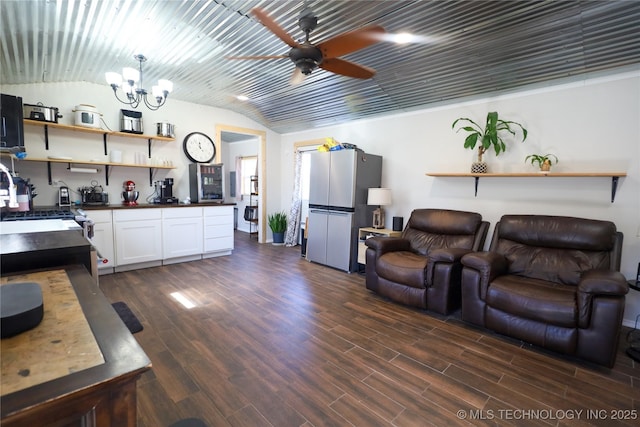 living area with ceiling fan with notable chandelier, dark wood-style floors, and vaulted ceiling