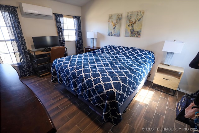 bedroom featuring wood finish floors, baseboards, and a wall unit AC