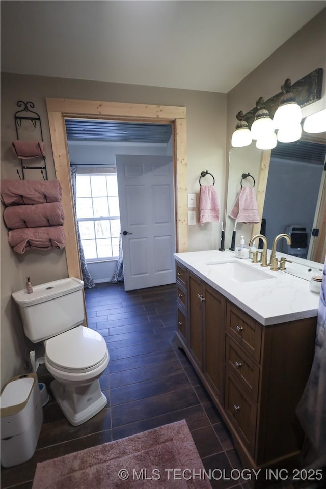 bathroom with toilet, vanity, and wood tiled floor