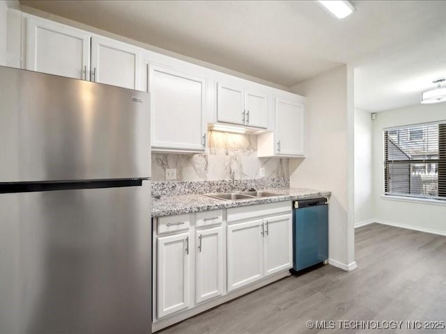 kitchen featuring tasteful backsplash, freestanding refrigerator, white cabinetry, a sink, and dishwasher