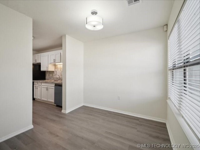 interior space with dark wood-type flooring, a sink, visible vents, and baseboards