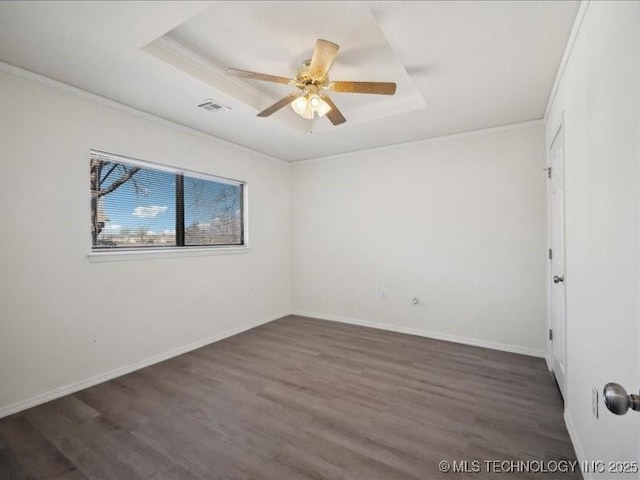 unfurnished room featuring visible vents, a raised ceiling, crown molding, and wood finished floors