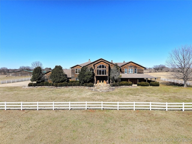 view of front of house with a rural view, a chimney, a front yard, and fence