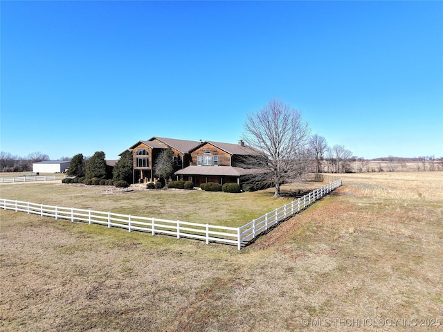 view of front facade with a rural view, fence, and a front lawn