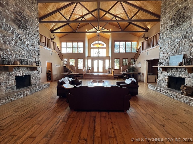 unfurnished living room featuring wooden ceiling, wood-type flooring, stairway, a stone fireplace, and a healthy amount of sunlight