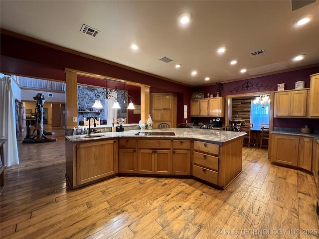 kitchen with light wood-type flooring, visible vents, and a sink