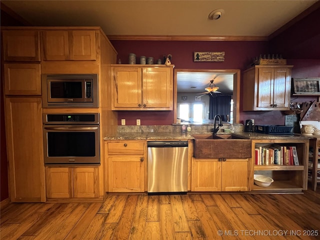 kitchen featuring light wood finished floors, ornamental molding, stainless steel appliances, and a sink