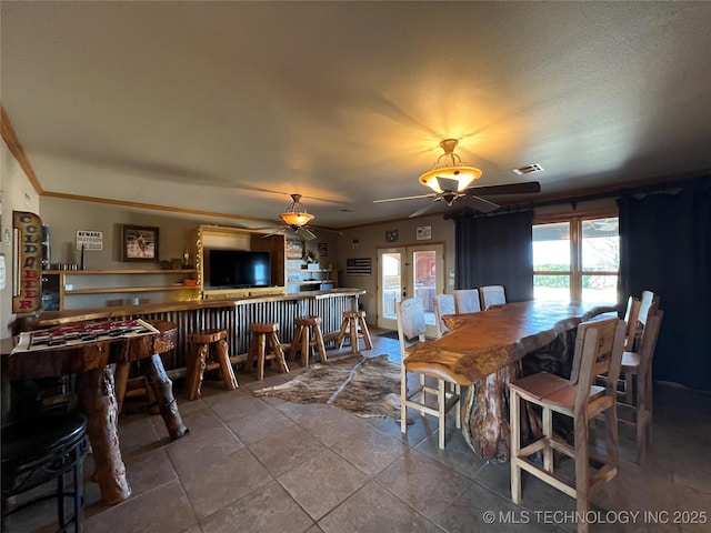 dining area featuring visible vents, a ceiling fan, tile patterned flooring, french doors, and a bar