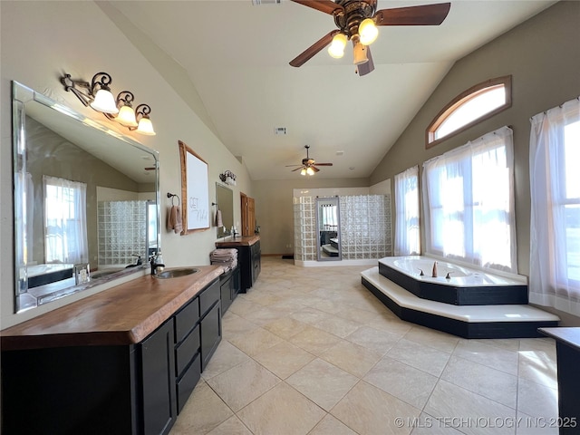 bathroom with lofted ceiling, two vanities, a sink, and a bath