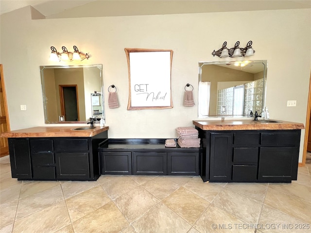 full bath featuring vaulted ceiling, two vanities, and a sink