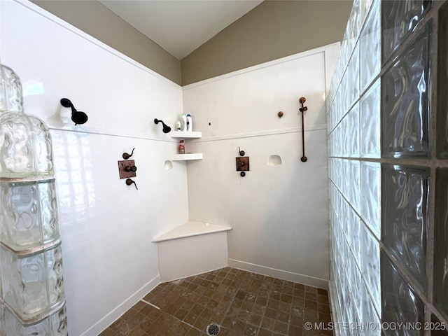 full bathroom with vaulted ceiling, walk in shower, and baseboards