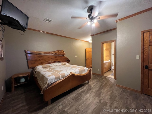 bedroom featuring wood finished floors, visible vents, baseboards, ornamental molding, and ensuite bath