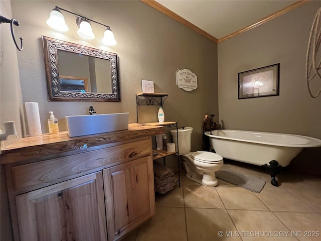 bathroom featuring a freestanding bath, toilet, ornamental molding, vanity, and tile patterned flooring