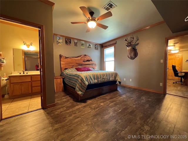 bedroom featuring crown molding, visible vents, light wood-style floors, ensuite bath, and baseboards