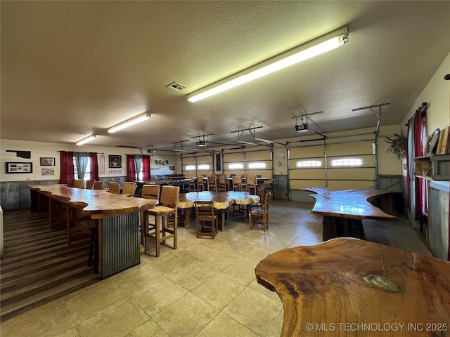 garage featuring a garage door opener, a wainscoted wall, and visible vents