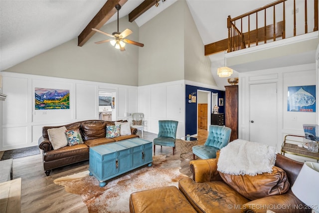 living room featuring a decorative wall, a ceiling fan, wood finished floors, high vaulted ceiling, and beamed ceiling