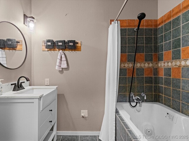 bathroom featuring tile patterned flooring, tiled shower / bath, baseboards, and vanity