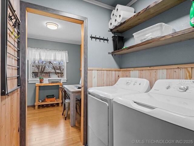 washroom with washer and dryer, wainscoting, wooden walls, light wood-type flooring, and laundry area