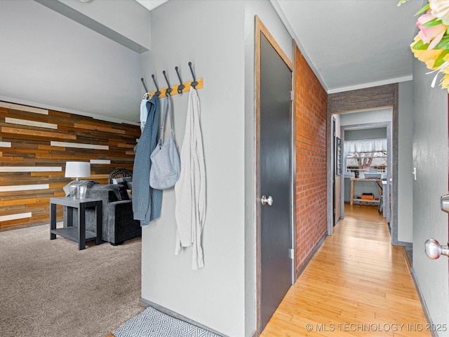 corridor featuring brick wall, carpet flooring, wood finished floors, and an accent wall