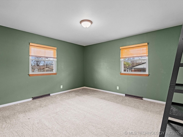 empty room with a wealth of natural light, visible vents, and carpet flooring