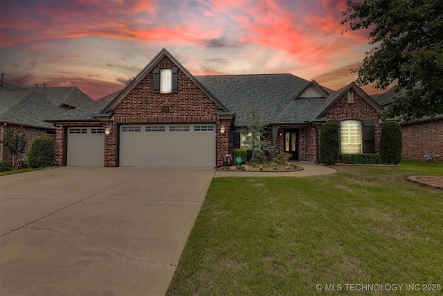 traditional home with an attached garage, a yard, a shingled roof, concrete driveway, and brick siding