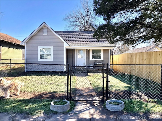 view of front of house with a fenced front yard, a gate, roof with shingles, and a front lawn