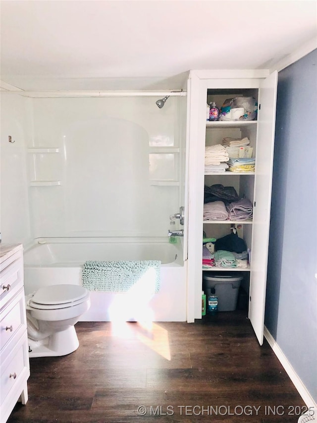 bathroom featuring toilet, wood finished floors, and shower / bathing tub combination