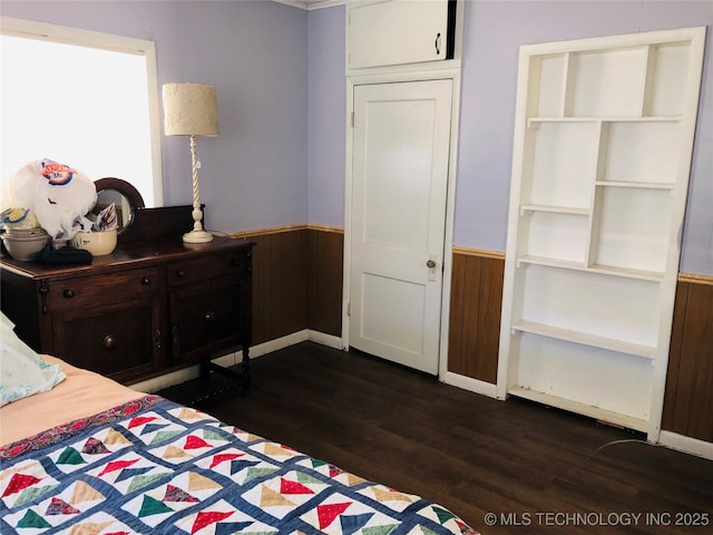 bedroom featuring a wainscoted wall, dark wood finished floors, and wood walls