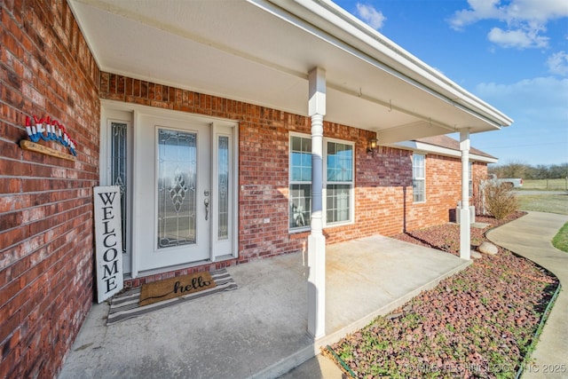 property entrance featuring brick siding and a porch