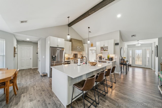 kitchen with light countertops, wood finished floors, visible vents, and stainless steel fridge with ice dispenser