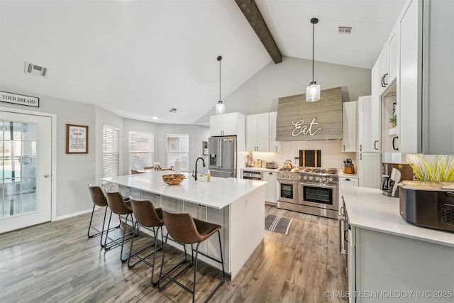 kitchen with beamed ceiling, a breakfast bar area, high quality appliances, and light wood-style floors