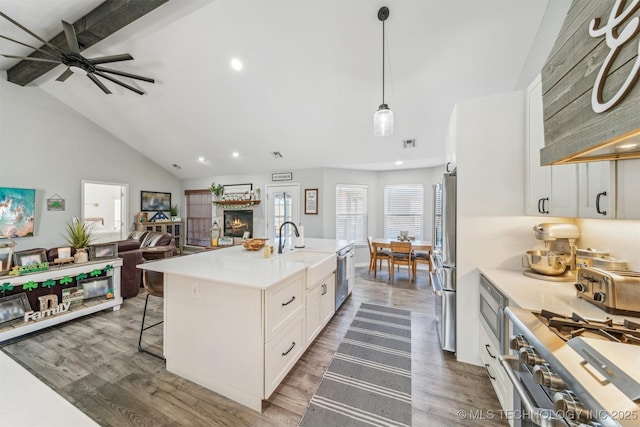 kitchen featuring dark wood finished floors, appliances with stainless steel finishes, open floor plan, white cabinetry, and a lit fireplace