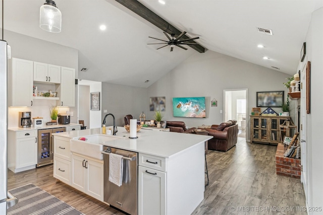 kitchen featuring light wood-style flooring, a sink, visible vents, stainless steel dishwasher, and beamed ceiling