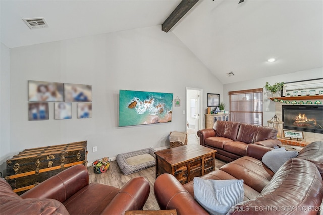 living room with visible vents, a tile fireplace, wood finished floors, high vaulted ceiling, and beam ceiling